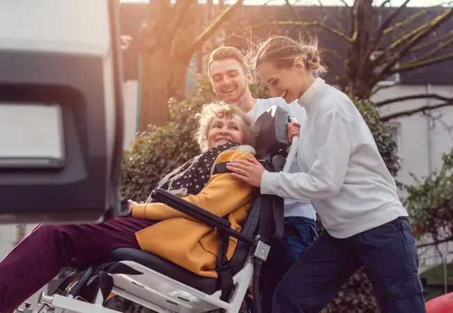 Caregivers helping woman in wheelchair