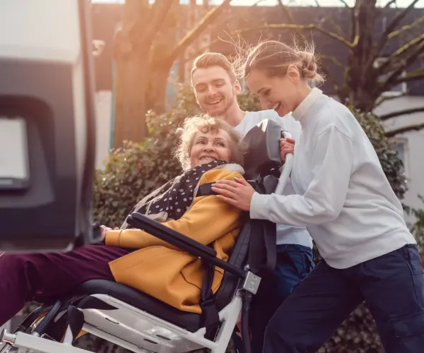 Caregivers helping woman in wheelchair